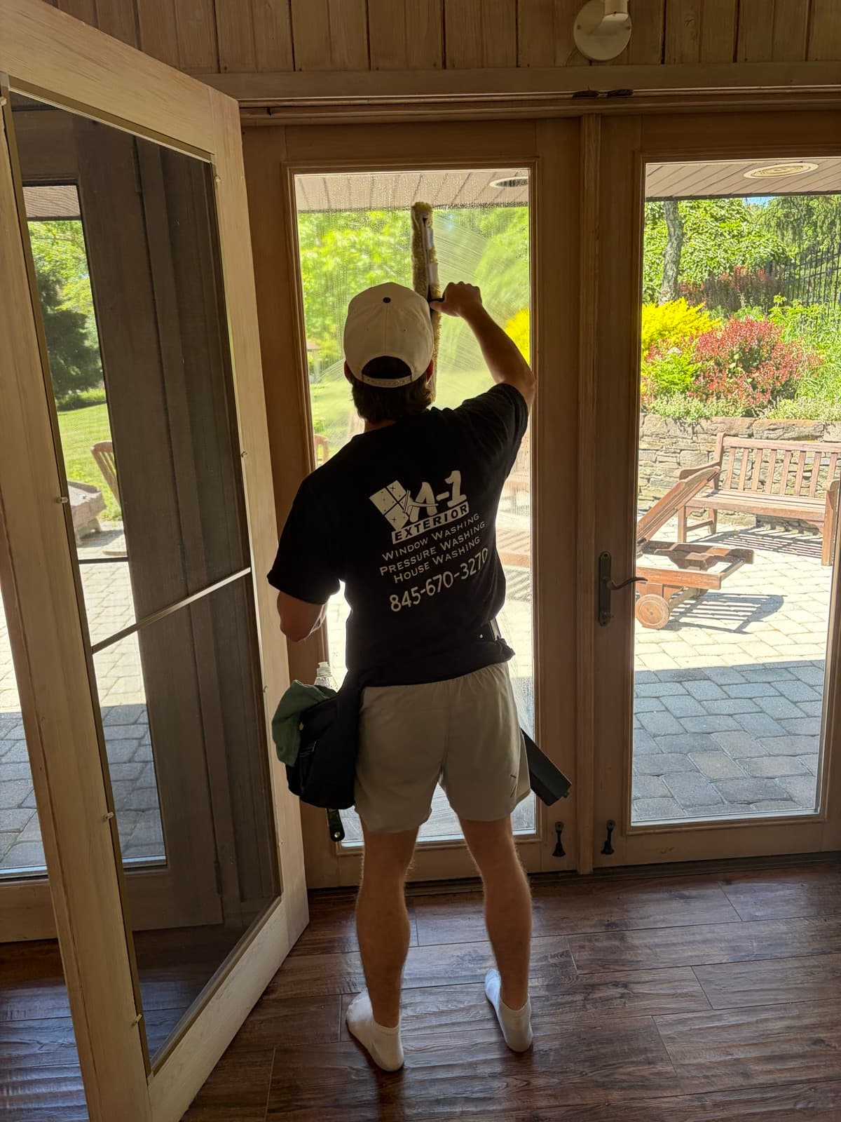 Anthony squeegeeing a tall interior French door to streak-free glass, A-1 Exterior shirt on his back
